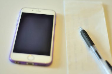 Beyaz arkaplanda izole edilmiş kalem ve cep telefonlu defter