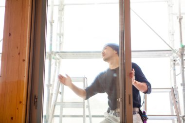 Ahşap bina inşaatında çalışan Asyalı genç bir inşaatçının portresi.