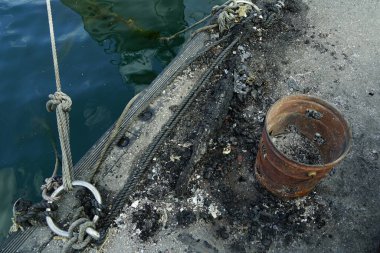 Paslı kutu ve yıpranmış rıhtım yüzeyinde ip.