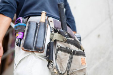 Aletleri olan erkek işçiyi kapat, alet kemeri olan inşaat işçisi. 