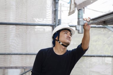 Asyalı genç inşaatçının ve şantiyenin portresi