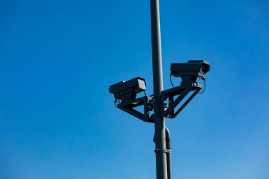 Gökyüzü arka planındaki sokakta güvenlik kamerası var.