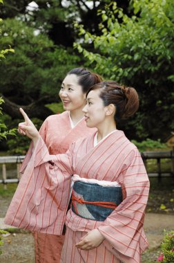 Parkta geleneksel Japon kimonosu giyen iki mutlu Asyalı kadın.