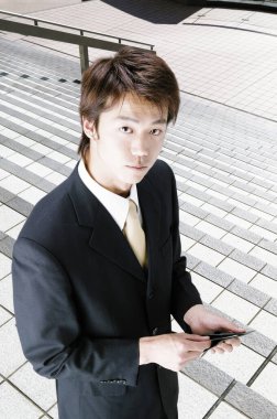 Genç bir Asyalı işadamının portresi merdivenlerde dikilip kameraya bakıyor.