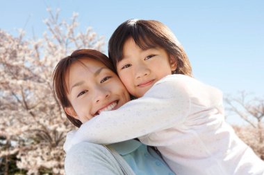 Anne ve kızı parkta sarılıyorlar.