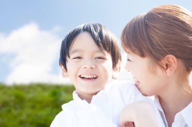Asyalı genç anne ve küçük oğlunun açık hava portresi. 