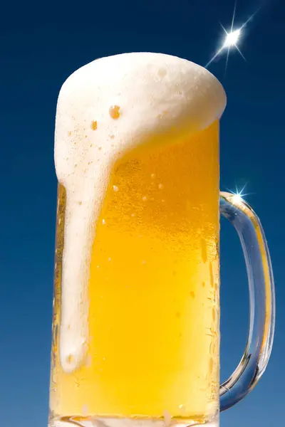 Glas Schäumendes Bier Vor Blauem Hintergrund — Stockfoto