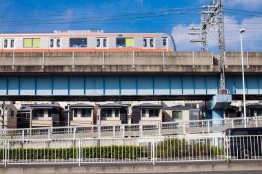 Modern tren mavi gökyüzünün altındaki binaların üzerinden geçiyor.