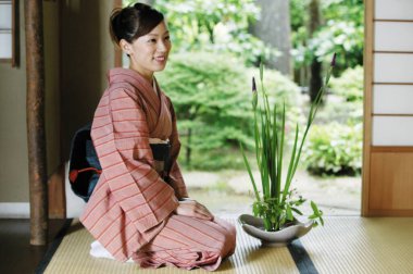 Geleneksel kimonolu genç Asyalı kadın lotus pozisyonunda oturuyor.