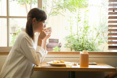 Genç Asyalı kadın kahvaltını kafede yapıyor.