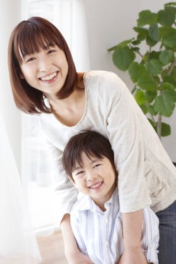 Gülümseyen kadın, kucaklayan neşeli genç çocuk.