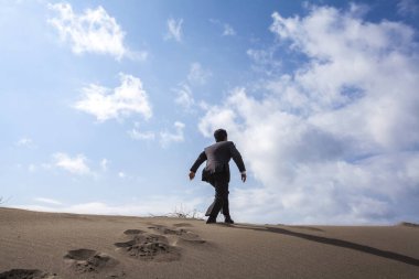 Asyalı işadamı kumsalda yürüyor, dikiz manzaralı. 