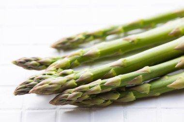 Beyaz masa arkaplanındaki yeşil kuşkonmaz manzarasını kapat