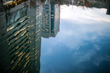 Şehirdeki modern binalar su birikintisine yansıyor. 