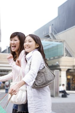 İki kadın binanın yanında gülüyor.