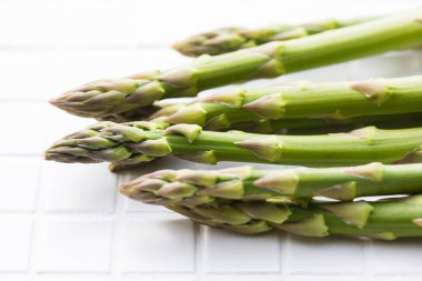 Beyaz masa arkaplanındaki yeşil kuşkonmaz manzarasını kapat