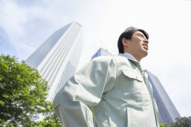 Asyalı işadamı elleri ceplerinde duruyor