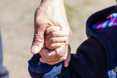 Oğul dışarıda babasının elini tutuyor. 