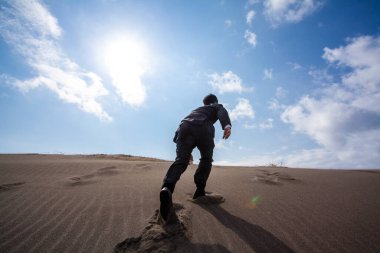 Asyalı işadamı kumsalda yürüyor, dikiz manzaralı. 