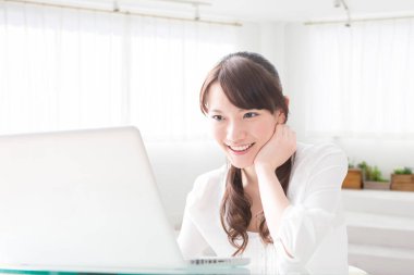 Dizüstü bilgisayarla çalışan gülümseyen Japon kadın.