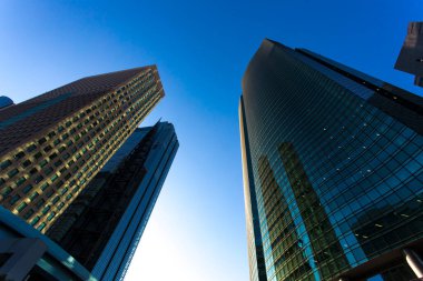 Mavi gökyüzüne uzanan modern cam gökdelenlerin alçak açılı görüntüsü