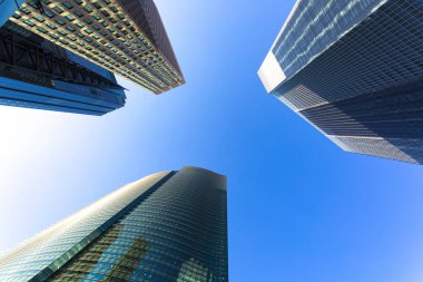 Mavi gökyüzüne uzanan modern cam gökdelenlerin alçak açılı görüntüsü