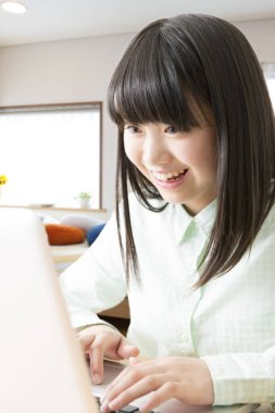 Evde dizüstü bilgisayar kullanan genç bir kadın. 