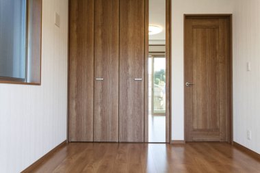 Ahşap kapısı, dolabı ve parketi olan boş bir oda.