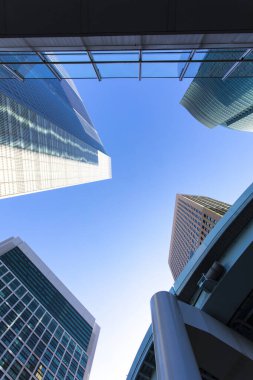Mavi gökyüzüne uzanan modern cam gökdelenlerin alçak açılı görüntüsü