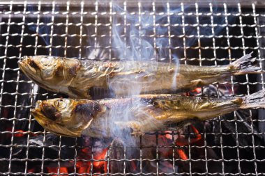 Izgarada balık pişirmek, manzarayı kapatın.