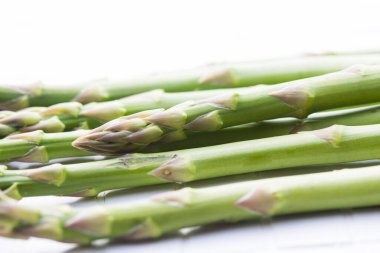 Beyaz masa arkaplanındaki yeşil kuşkonmaz manzarasını kapat