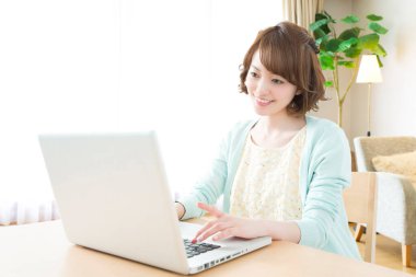 Evde dizüstü bilgisayar kullanan genç bir kadın.