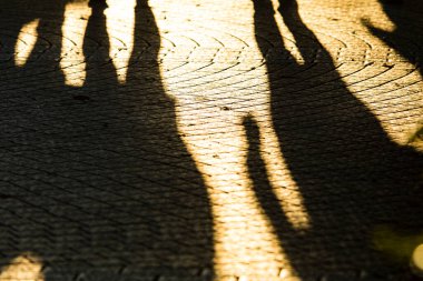 Gün batımında sokakta yürüyen insanların gölgeleri.