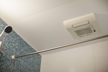 interior of bathroom with shower and air intake on ceiling 