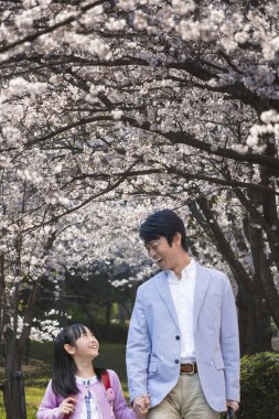 Genç Asyalı baba ve kızı parkta yürüyor. 