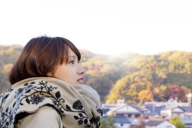 Genç bir kadın sonbahar manzarasının arka planına bakıyor..