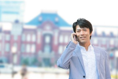 İş adamı sokakta yürürken akıllı telefon kullanıyor. 