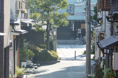 Birkaç bina ve bir ağaç olan dar bir cadde. 