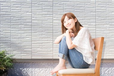 Duvarda oturan genç bir kadın. 