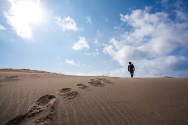 Asyalı işadamı kumsalda yürüyor, dikiz manzaralı. 