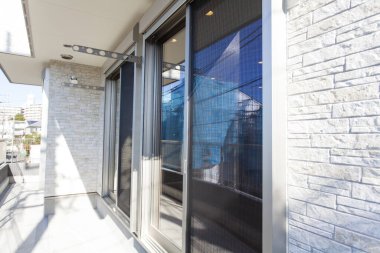 Sürgülü cam kapıları ve tuğla duvarı olan modern balkon.