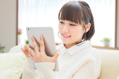 Evdeki koltukta dijital tablet kullanan bir kadın. 