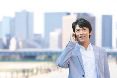 Genç işadamı sokakta cep telefonuyla konuşuyor.