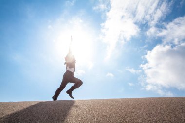 Resmi takım elbiseli Asyalı işadamı kumsalda koşuyor.