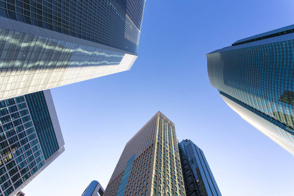 A low-angle view of modern glass skyscrapers reaching towards a blue sky