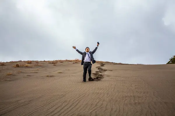アジアのビジネスマンは砂浜で腕を上げる — ストック写真