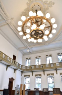 Tarihi mahkeme salonunda asılı büyük, süslü bir avize, uzun pencereli.