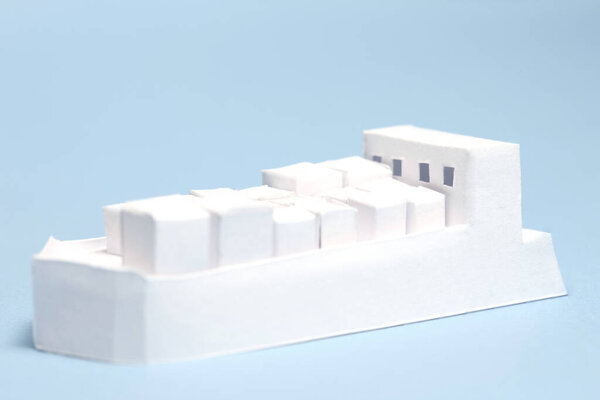 White architectural model featuring geometric buildings against blue background