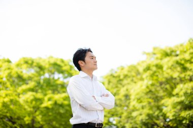 Yakışıklı genç iş adamının portresi çapraz kollarla durup parka bakıyor.