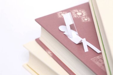 Beyaz arka planda izole edilmiş kağıt bir insan figürüne sahip kitap yığını
